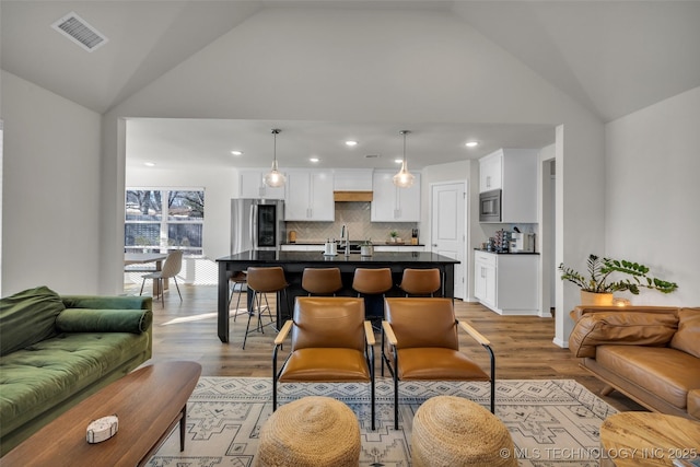 living room featuring light hardwood / wood-style floors, lofted ceiling, and sink