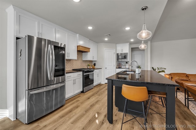 kitchen featuring backsplash, a center island with sink, white cabinets, sink, and stainless steel appliances