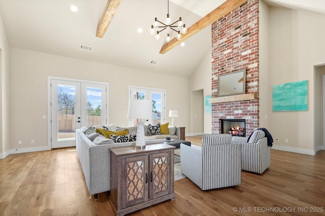 living room featuring beamed ceiling, wood-type flooring, a fireplace, and french doors