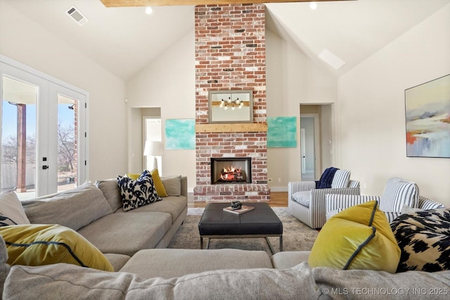 living room with a brick fireplace, light hardwood / wood-style floors, lofted ceiling, and french doors