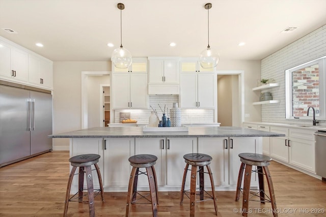 kitchen with a kitchen island, white cabinetry, stainless steel appliances, and tasteful backsplash