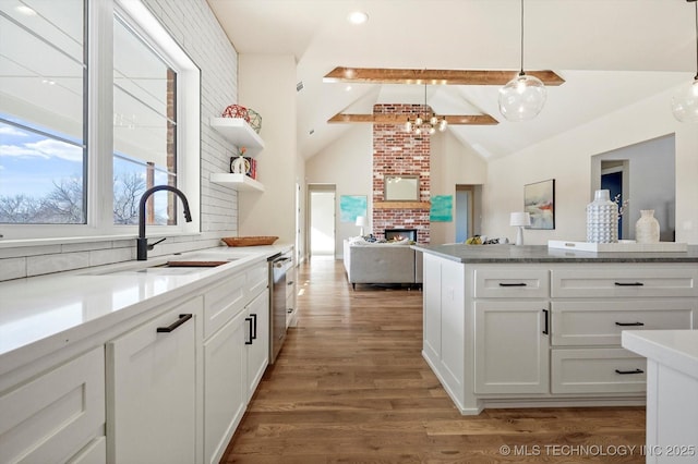 kitchen with lofted ceiling with beams, sink, tasteful backsplash, decorative light fixtures, and white cabinetry