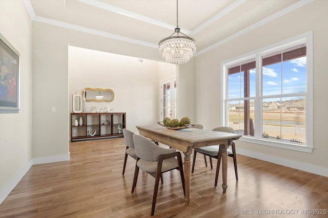 dining room featuring hardwood / wood-style flooring, an inviting chandelier, a tray ceiling, and ornamental molding