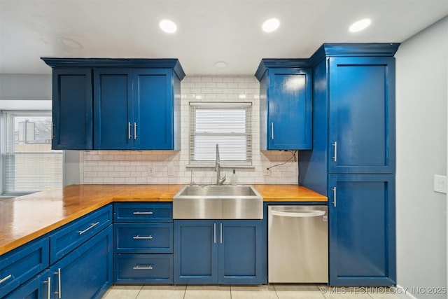 kitchen with sink, blue cabinetry, dishwasher, butcher block counters, and backsplash