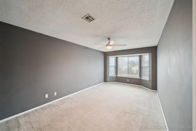 spare room featuring light carpet, a textured ceiling, and ceiling fan