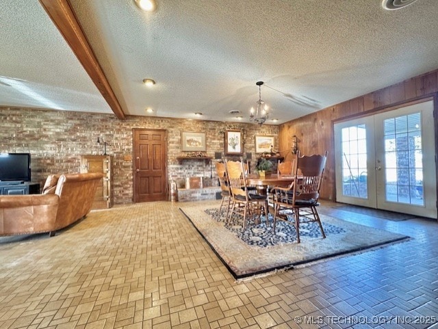 dining room featuring french doors, beamed ceiling, a textured ceiling, and brick patterned floor