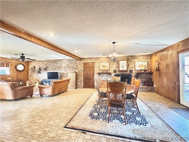 dining area featuring wooden walls, a wealth of natural light, beamed ceiling, and a textured ceiling