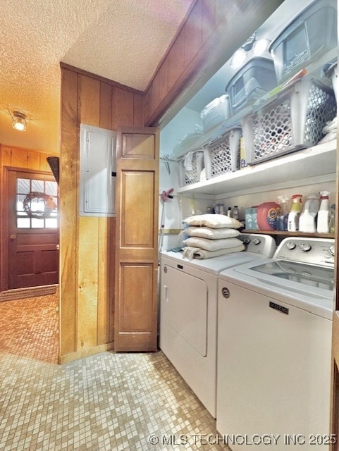 washroom with laundry area, washing machine and dryer, a textured ceiling, and wood walls