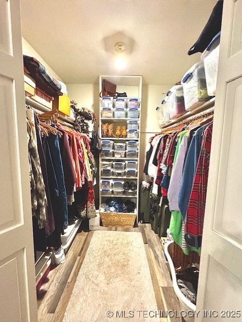 walk in closet with wood finished floors