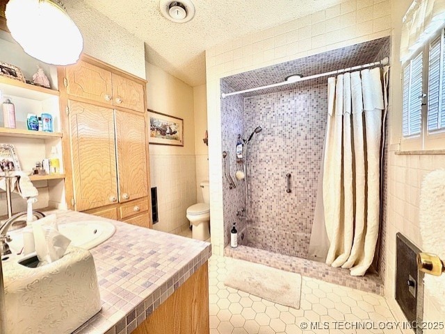 full bath featuring a textured ceiling, toilet, a tile shower, and tile walls