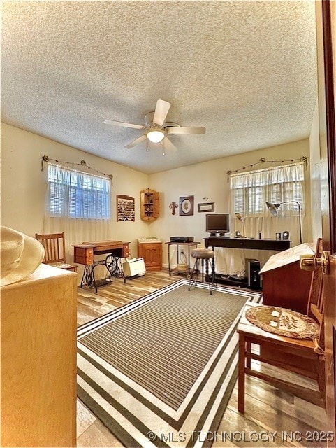 rec room with ceiling fan, a textured ceiling, and wood finished floors