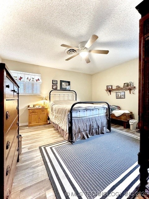 bedroom featuring visible vents, a textured ceiling, light wood-type flooring, and a ceiling fan