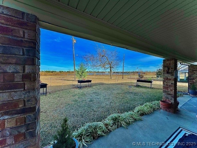 view of yard featuring a patio area, fence, and a rural view