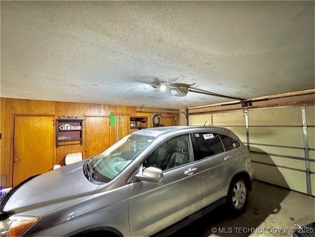 garage featuring a garage door opener and wood walls