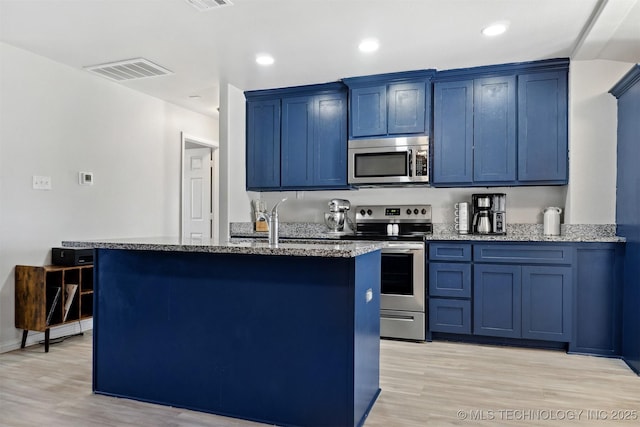 kitchen featuring light stone countertops, light wood-type flooring, stainless steel appliances, blue cabinets, and a kitchen island