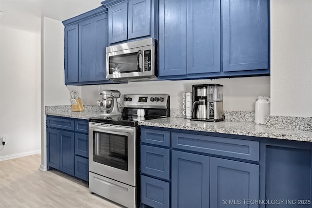 kitchen featuring light stone counters, blue cabinets, stainless steel appliances, and light wood-type flooring