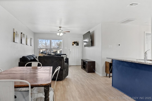 dining space featuring ceiling fan, light wood-type flooring, and sink