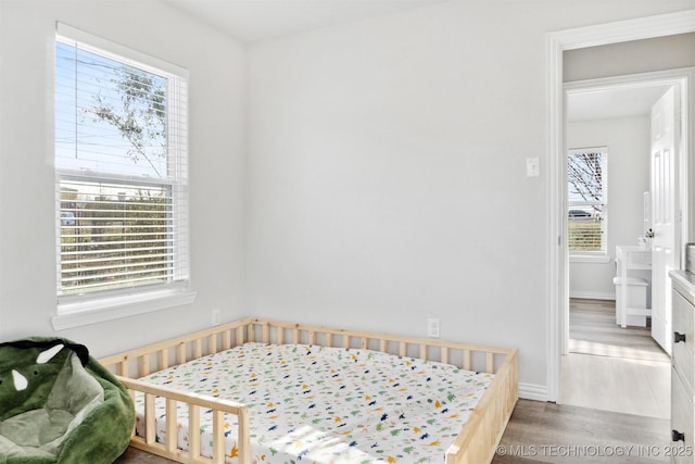 bedroom with a nursery area and wood-type flooring