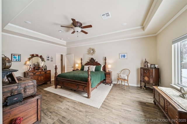 bedroom with visible vents, a raised ceiling, and wood finished floors