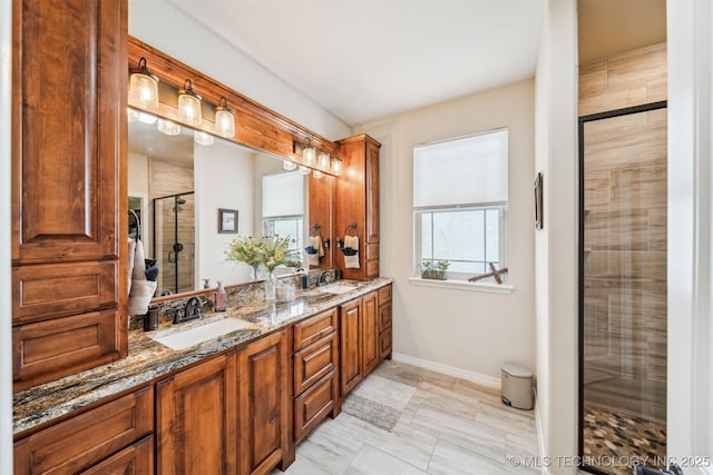 full bath with double vanity, a stall shower, baseboards, and a sink