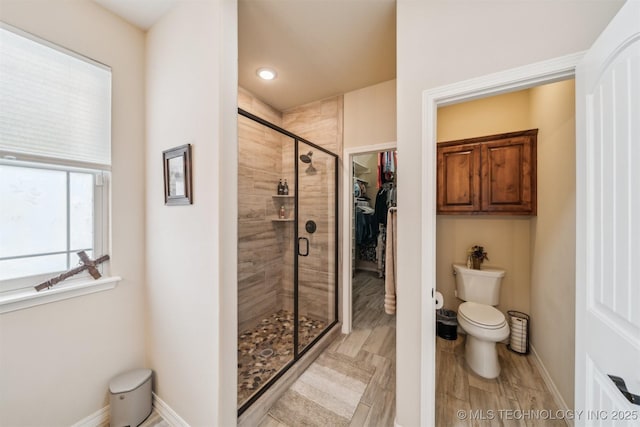 full bath with a stall shower, toilet, and baseboards