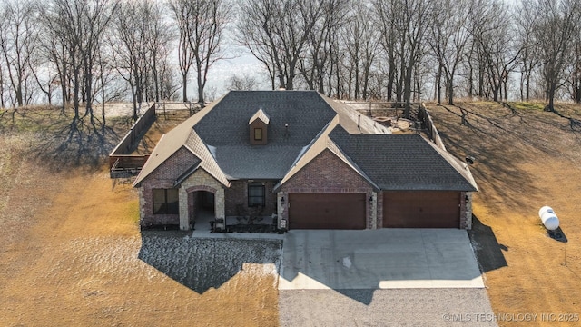 view of front facade featuring a garage, stone siding, roof with shingles, and driveway