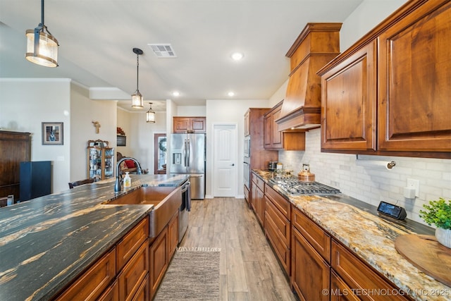 kitchen with tasteful backsplash, visible vents, light wood-style flooring, appliances with stainless steel finishes, and a sink