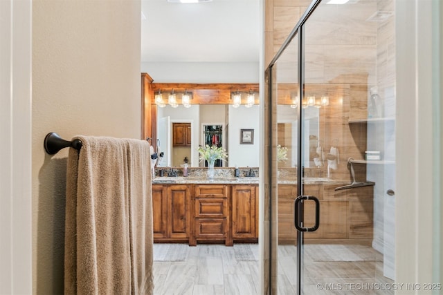 bathroom with a stall shower, a sink, and double vanity