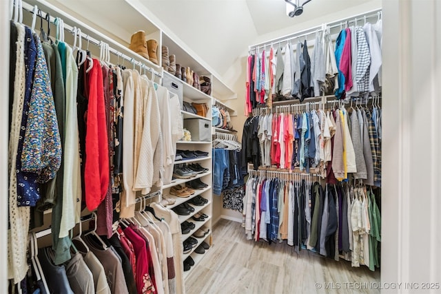 walk in closet with hardwood / wood-style floors and vaulted ceiling