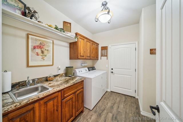 washroom with cabinets, light hardwood / wood-style flooring, washer and clothes dryer, and sink