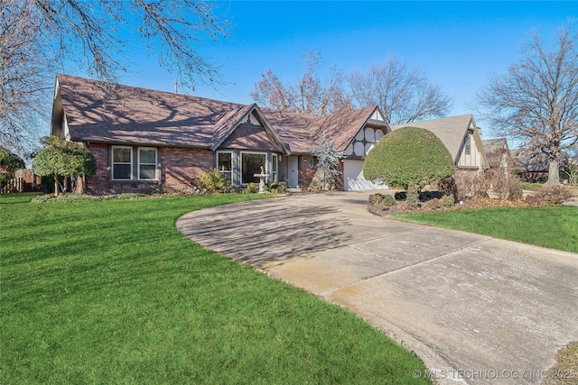 english style home featuring a front lawn, a garage, brick siding, and driveway