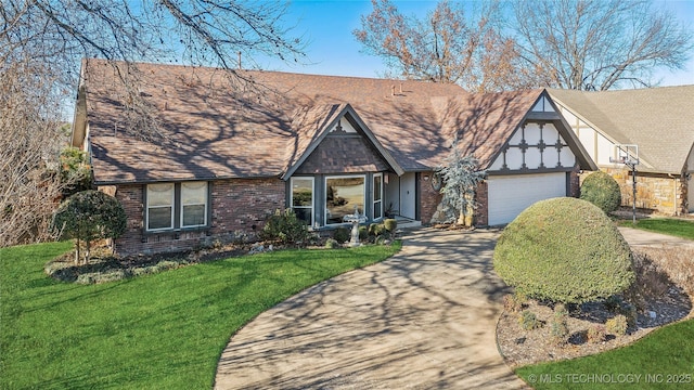 tudor house with a front lawn, a garage, brick siding, and driveway