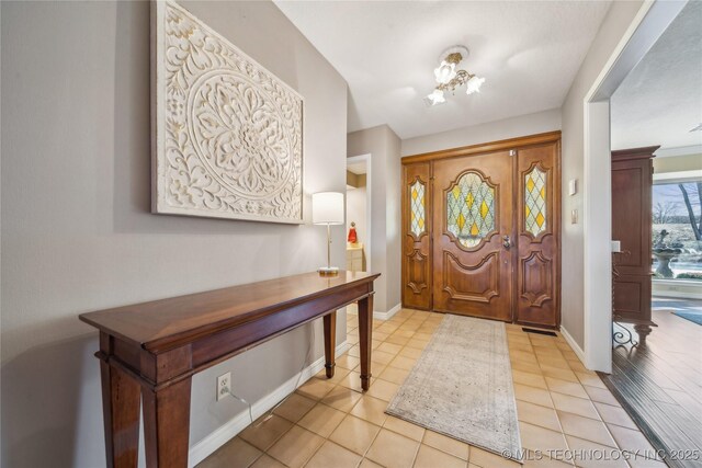 foyer with baseboards and light tile patterned flooring