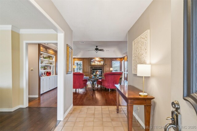 entryway featuring a glass covered fireplace, wood finished floors, baseboards, and ceiling fan