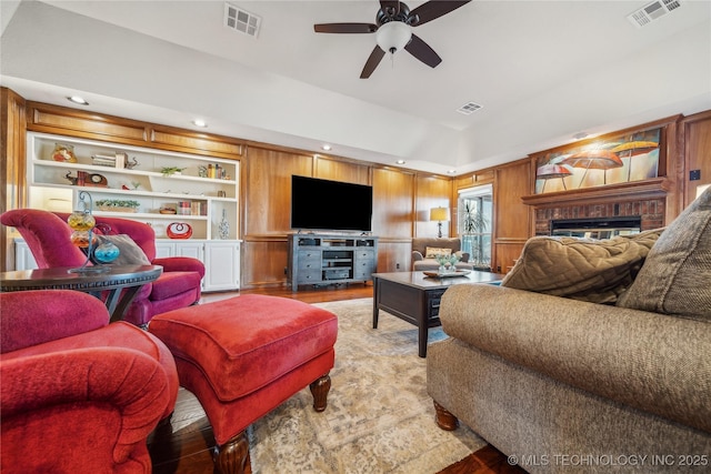 living area with visible vents, a brick fireplace, and light wood finished floors