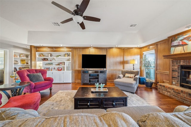 living area with hardwood / wood-style flooring, built in features, a fireplace, and visible vents