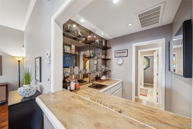 bar featuring tile patterned flooring, visible vents, crown molding, wet bar, and a sink