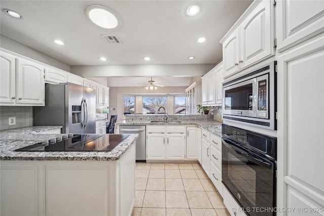 kitchen featuring black appliances, white cabinets, a peninsula, and a sink