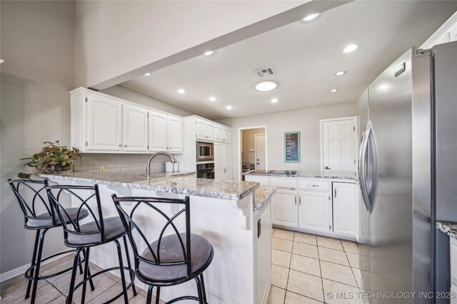 kitchen with white cabinets, a peninsula, black appliances, and a sink