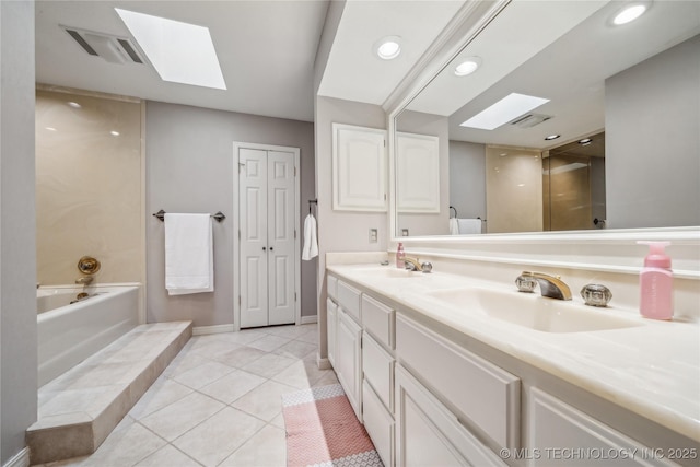 bathroom featuring a skylight, a bath, visible vents, and a sink