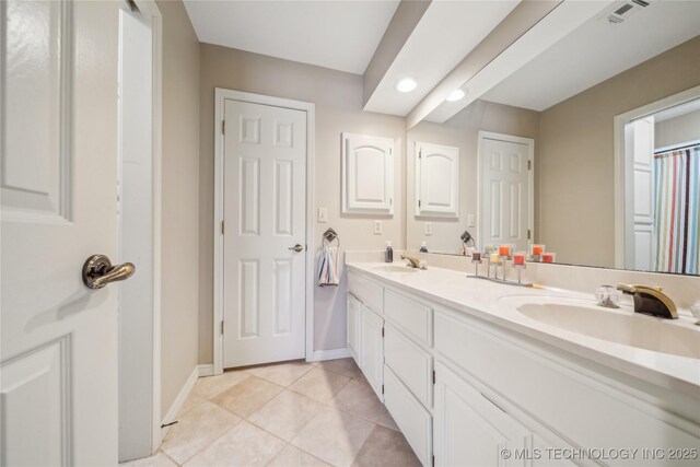 full bathroom featuring a sink, baseboards, double vanity, and tile patterned flooring