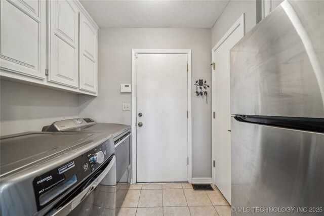 washroom with light tile patterned floors, cabinet space, and washer and dryer