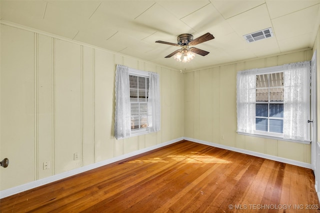 spare room featuring ceiling fan, a wealth of natural light, and wood-type flooring