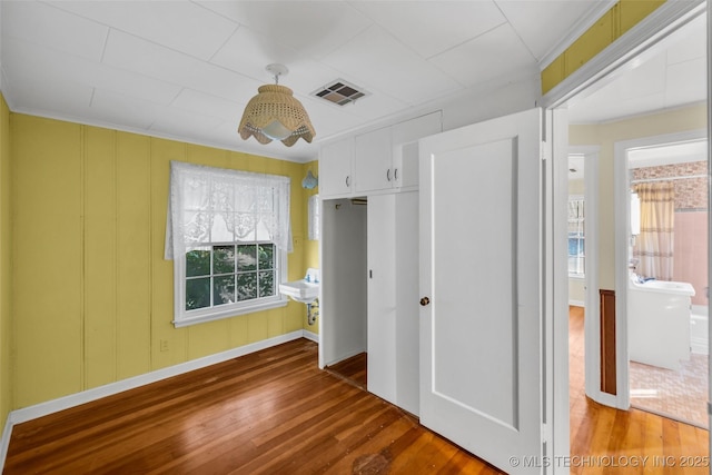 unfurnished bedroom with ensuite bathroom, ornamental molding, and hardwood / wood-style floors