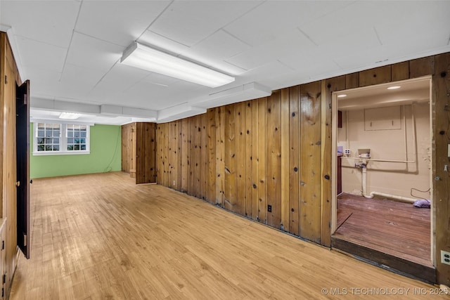 basement with light hardwood / wood-style floors and wooden walls