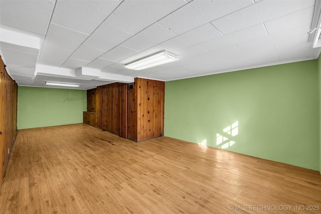 unfurnished room featuring light wood-type flooring and wooden walls