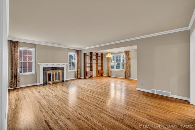 unfurnished living room featuring ornamental molding, a premium fireplace, and a healthy amount of sunlight