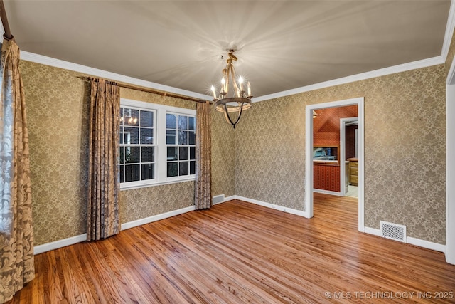 unfurnished dining area with hardwood / wood-style floors, crown molding, and an inviting chandelier