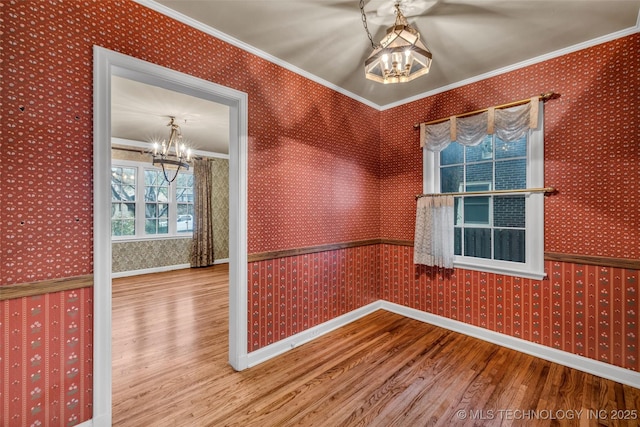 unfurnished room with hardwood / wood-style flooring, crown molding, and an inviting chandelier