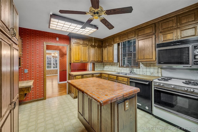 kitchen with black appliances, a kitchen island, sink, tile countertops, and ceiling fan